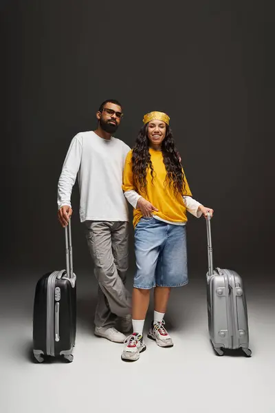 Couple dressed in fashionable attire stands confidently, preparing for a journey together. — Stock Photo