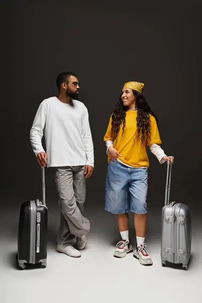 A stylish couple stands with luggage, smiling and ready for their journey together. — Stock Photo