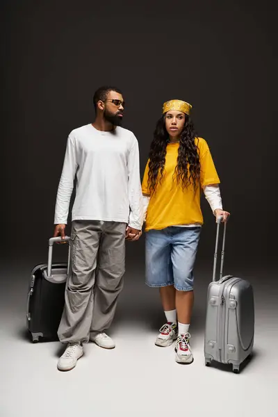 A stylish couple stands confidently, hand in hand, with chic luggage ready for travel. — Stock Photo