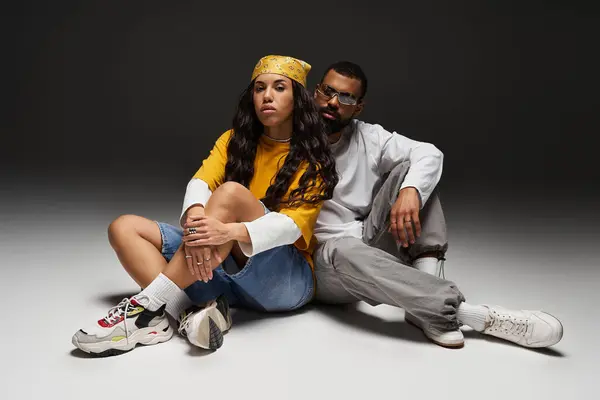 A fashionable couple relaxes together, showcasing their unique styles in an artistic studio. — Stock Photo