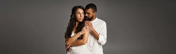 A stylish couple embraces lovingly while showcasing their fashionable looks in a minimalist setting. — Stock Photo