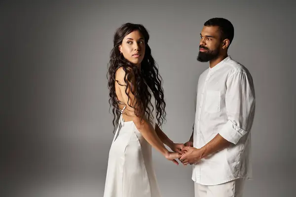 A fashionable couple holds hands gently while gazing at each other, radiating love and connection. — Stock Photo