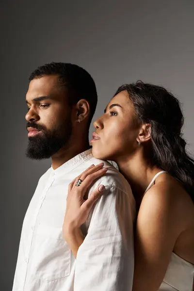 Una pareja de moda se encuentra cerca en un estudio minimalista, abrazando su conexión y estilo. - foto de stock