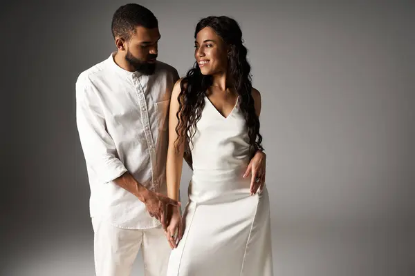 A stylish couple shares a loving moment, highlighting their outfits against a plain backdrop. — Stock Photo