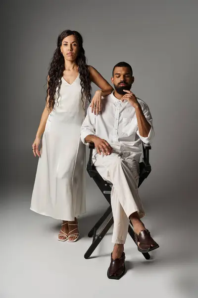 Модная пара стоит вместе, демонстрируя свою любовь и стиль на нейтральном фоне. — стоковое фото