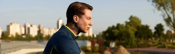 A handsome young man strolls along the riverside, lost in thought under the warm sun. — Stock Photo