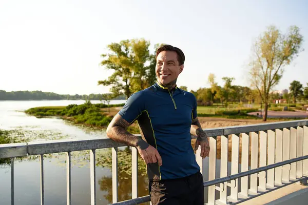 A young man strolls by the water, smiling in the sunlight. — Stock Photo