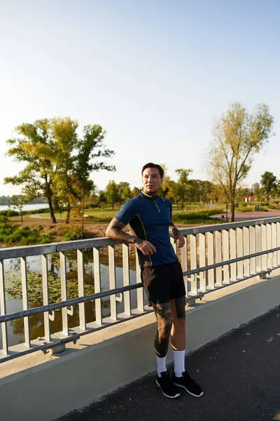 Handsome young man pauses to take in the serene views while walking near the riverbank at sunset. — Stock Photo