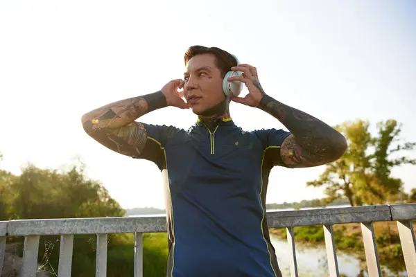 Handsome young man listens to music while strolling by the river under a clear sky — Stock Photo