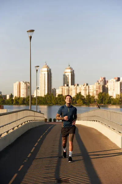 A young man jogs joyfully by the waterfront on a beautiful day amidst the cityscape. — Stock Photo