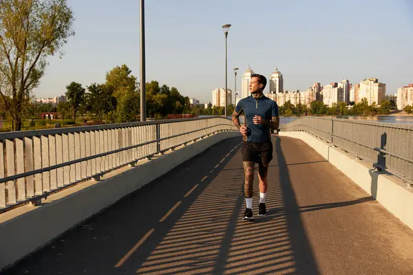 A handsome young man strolls down a peaceful riverside walkway, relishing the warm evening light. — Stock Photo