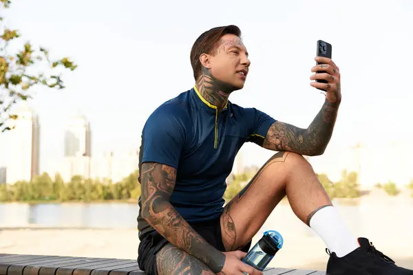A young and attractive man takes a break during his walk, admiring the view and using his phone. — Stock Photo
