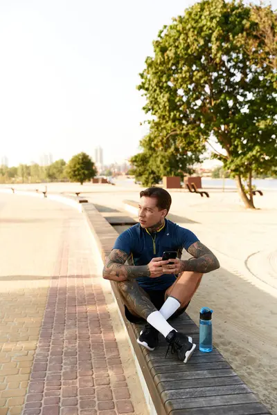 Young man with tattoos takes a break on a bench, enjoying the warm evening light. — Stock Photo