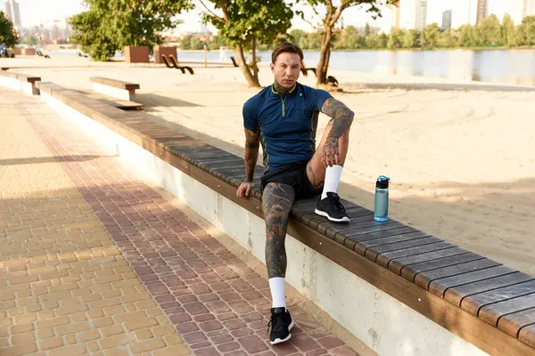 Un joven con estilo se relaja junto al río, disfrutando del sol y el paisaje. - foto de stock