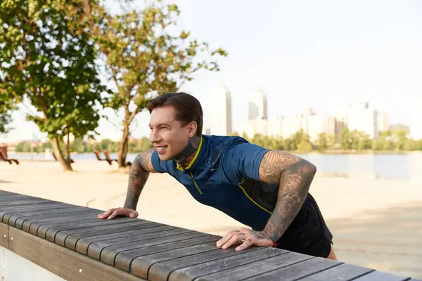 Um jovem com tatuagens está ativamente se engajando em exercícios ao longo de um caminho panorâmico à beira-mar.. — Fotografia de Stock