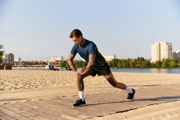 A handsome young man stretches while taking a leisurely walk by the riverside, enjoying nature. — Stock Photo