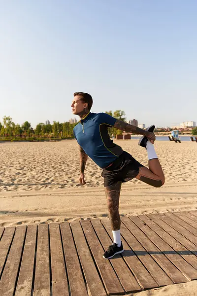 Handsome young man stretches his body on a warm sunny day by the beach, enjoying fresh air. — Stock Photo