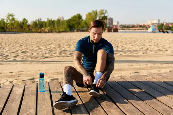 Young man is focused on tying his shoelaces before enjoying a refreshing walk on the beach. — Stock Photo