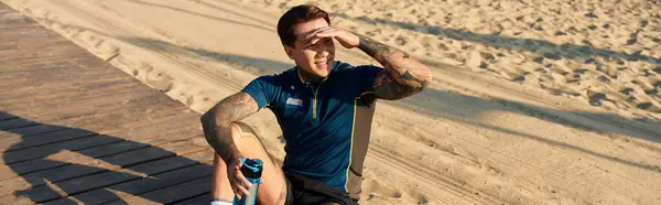 Handsome young man takes a break on a sandy path while enjoying the warm sunshine during his walk. — Stock Photo