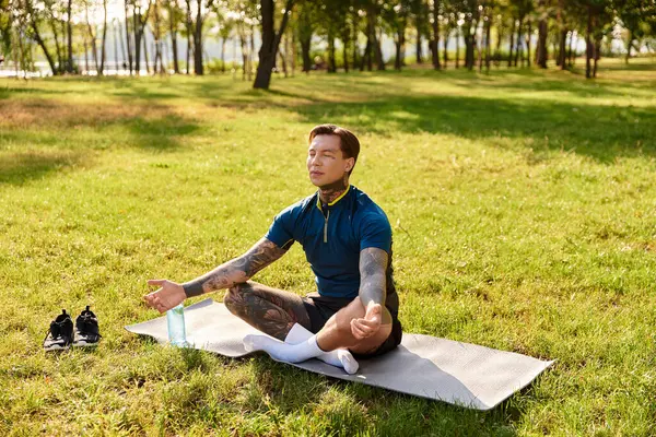 Un joven se sienta pacíficamente en un parque, practicando la atención plena en medio de la serenidad de la naturaleza. - foto de stock
