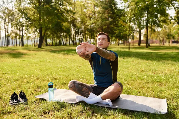 Bel giovanotto si allunga tranquillamente su un tappetino da yoga in un parco verde durante la mattina. — Foto stock