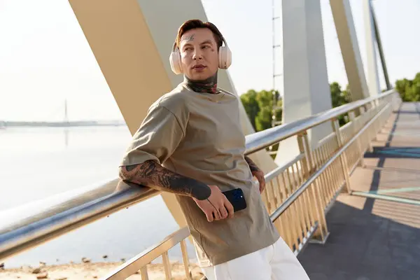 A young man strolls leisurely on a scenic bridge, listening to music while taking in the view. — Stock Photo