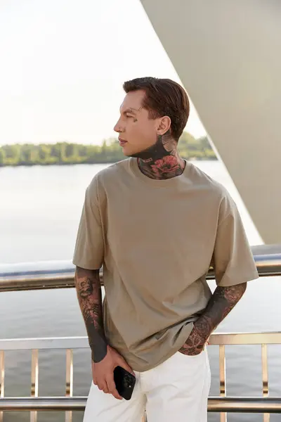 A young man dressed casually strolls along a waterfront, soaking in the beautiful surroundings. — Stock Photo