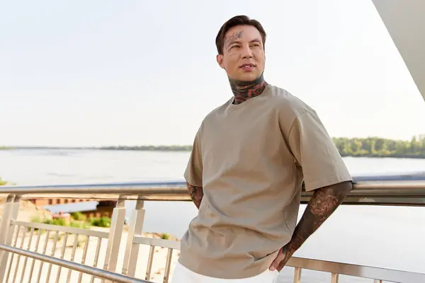 A young man strolls along a riverside promenade, exuding confidence and style during a bright day. — Stock Photo