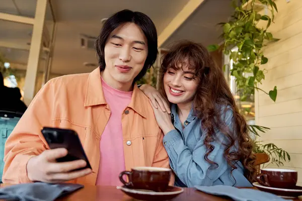 Two multicultural friends enjoy each others company while sharing smiles and laughter over coffee. — Stock Photo