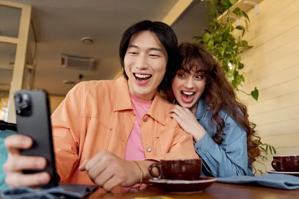 Two young friends enjoy each other company while sharing a laugh at a local cafe. — Stock Photo