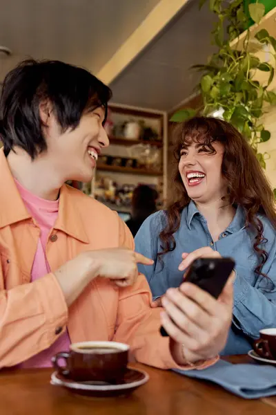 Two friends laugh together in a cafe, enjoying coffee and each other's company in blissful harmony. — Stock Photo