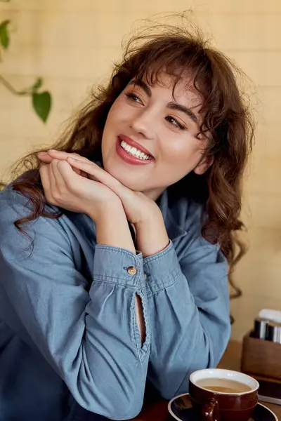 Young woman smiles over coffee in a lively cafe setting. — Stock Photo