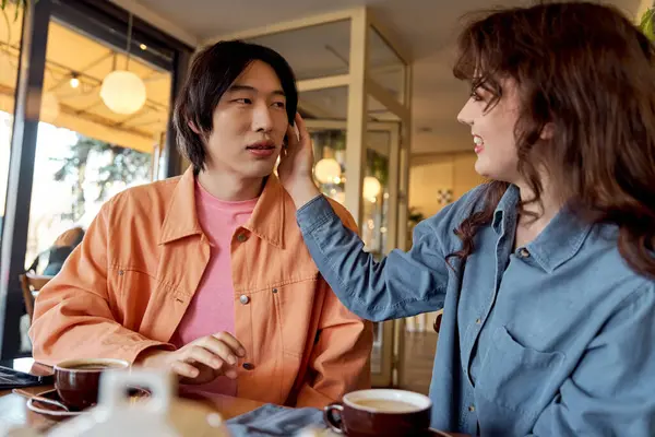 A young multicultural couple enjoys their time in a cafe while playfully connecting. — Stock Photo