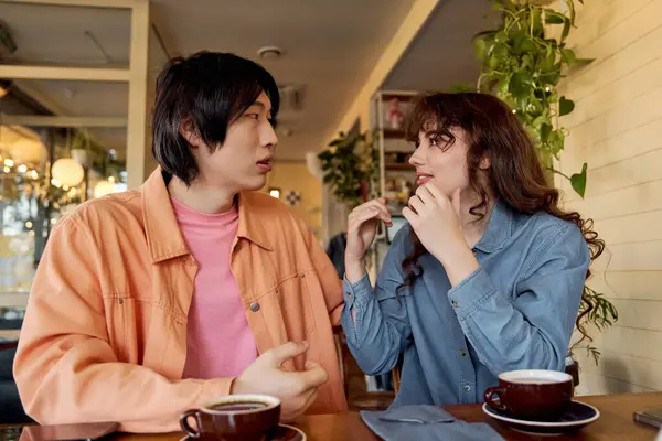 Two young friends share a joyful conversation over coffee in a vibrant cafe atmosphere. — Stock Photo