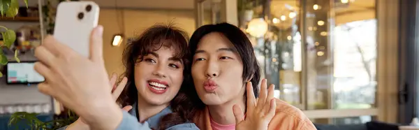 Two friends enjoy a lighthearted moment while taking a selfie in a vibrant cafe, banner — Stock Photo