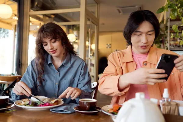Due amici assaporano un delizioso brunch mentre condividono le risate in un vivace caffè. — Foto stock