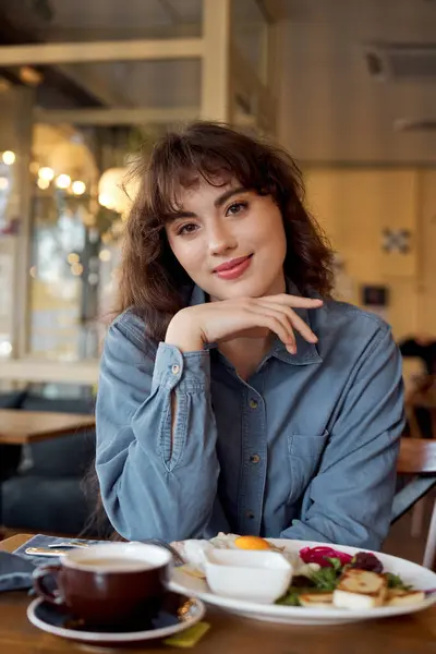 Young beautiful enjoying a delightful breakfast in a vibrant cafe — Stock Photo