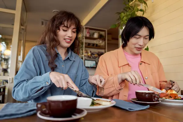 Due amici godono il loro pasto insieme, assaporando cibo delizioso e risate in un caffè. — Foto stock