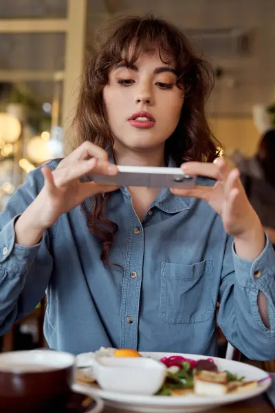 Mujer está tomando una foto de su comida en la cafetería, influencer o blogger de alimentos - foto de stock