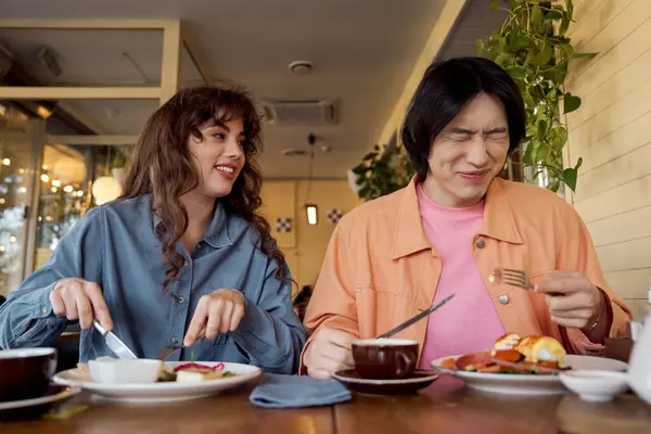 Two friends, a young man and woman, are enjoying a delightful meal, sharing smiles and bliss. — Stock Photo