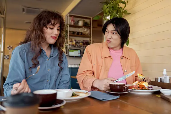 Two friends are having a delightful time at a cafe, sharing food and joy in each other's company. — Stock Photo