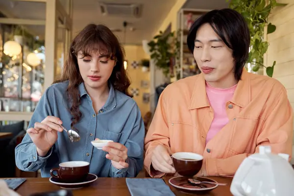 Two friends share a warm moment with tea, surrounded by a cozy cafe atmosphere. — Stock Photo