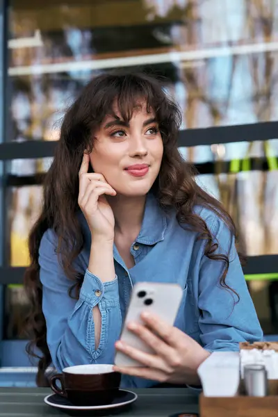 In a vibrant cafe, a young woman smiles while enjoying coffee and connecting with friends. — Stock Photo