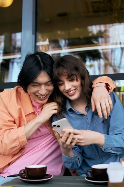Young friends enjoy each other's company while exploring their phones in a vibrant cafe. — Stock Photo