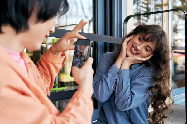 Ein junger asiatischer Mann fängt das lächelnde Glück seiner Freundin in einem charmanten Café-Ambiente ein. — Stockfoto