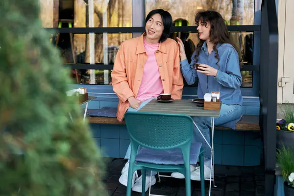 Two young friends, a man and woman, enjoy each others company at a cafe, sharing smiles. — Stock Photo