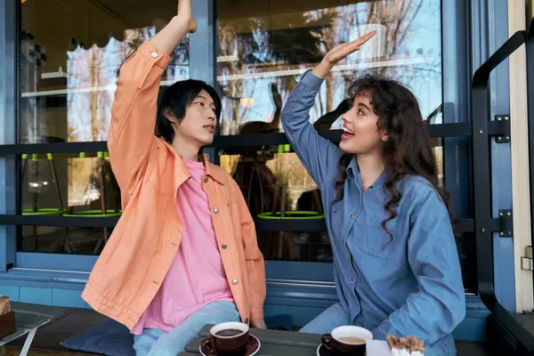 Two friends enjoy a lighthearted conversation while sipping coffee at a cozy cafe. — Stock Photo