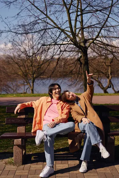 Young friends sitting joyfully in a serene park, soaking up the sun and sharing laughter. — Stock Photo