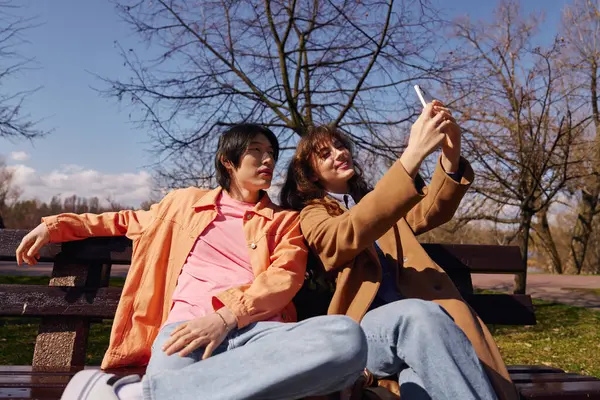 Two young friends relax and capture joyful memories in a serene park setting. — Stock Photo
