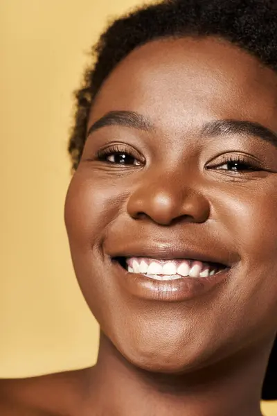 Luminosa impostazione studio mette in evidenza una pelle luminosa e sorriso gioioso della donna, sottolineando la bellezza. — Foto stock